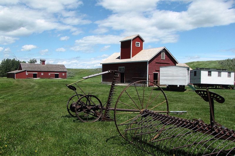 Red historic ranch buildings and old farm machinery at Bar U Ranch National Historic Site