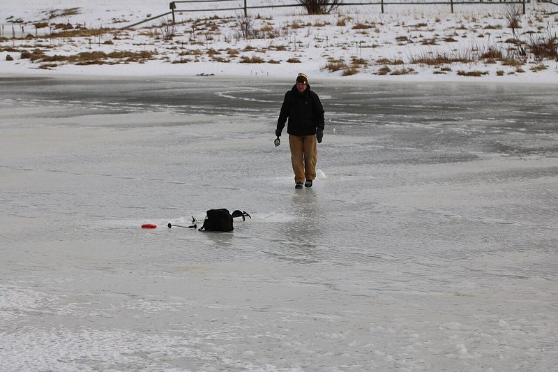 Adult ice fishing on a frozen lake
