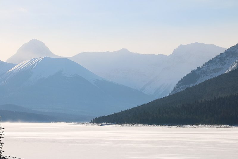 Frozen, snow-covered lake below mountains